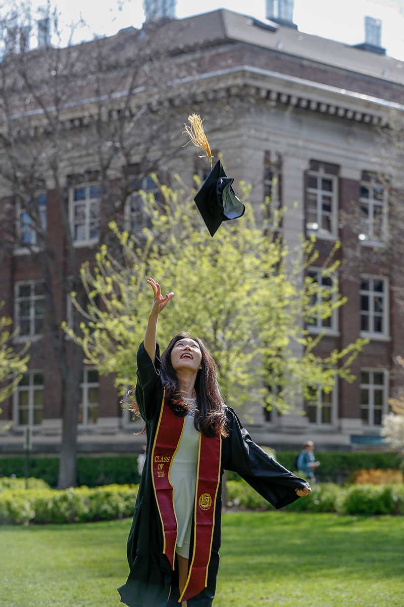 A graduate throwing her mortarboard in the air