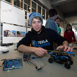 A student wearing a Tesla Works sweatshirt with a remote-controlled car